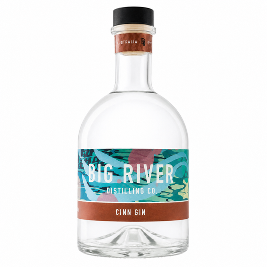 A bottle of Big River Distilling Co. Cinn Gin with a clear glass body, a black screw cap, and a colorful label featuring teal, pink, and brown tropical-style artwork.