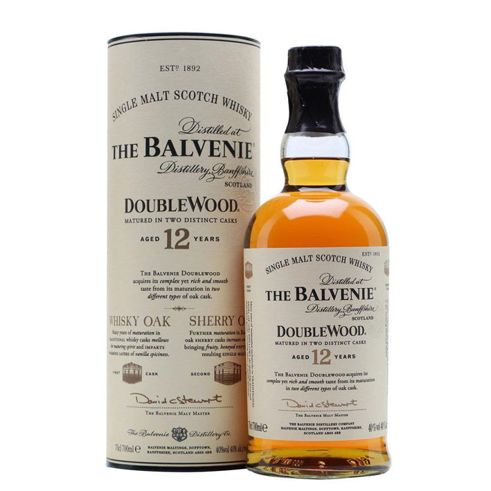 A bottle of The Balvenie Double Wood 12 years single malt Scotch whisky next to its cylindrical cardboard packaging.
